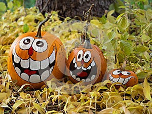 Three Smiling Painted Halloween Pumpkins with a Tree Trunk in th