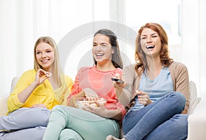 Three smiling teenage girl watching tv at home