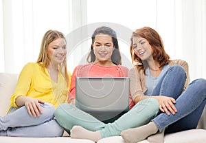 Three smiling teenage girls with laptop at home
