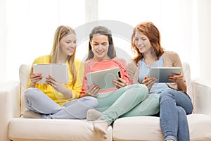 Three smiling teenage girls with tablet pc at home