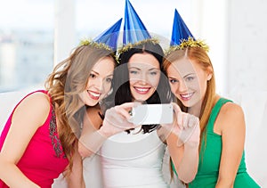 Three smiling women in hats having fun with camera