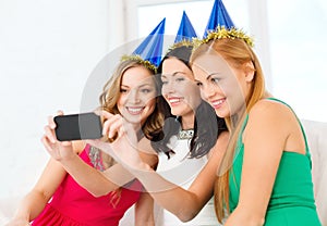 Three smiling women in hats having fun with camera