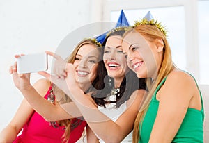 Three smiling women in hats having fun with camera