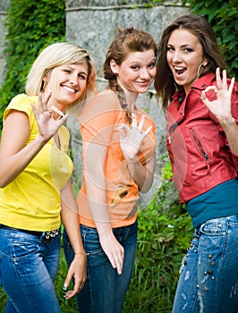 Three smiling women showing okey