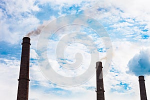 Three smoke stacks of the industrial plant against the cloudy sk