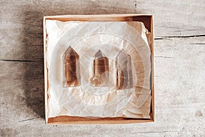 Three smoky natural quartz crystals in a kraft paper box on wooden background. Top view. Copy, empty space for text