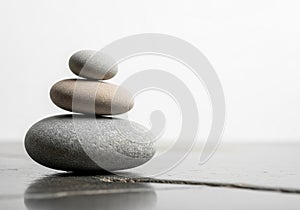Three smooth stones are stacked in a pyramid shape on a