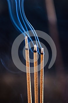 Three smouldering incense sticks with smoke