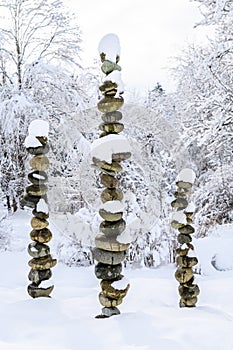 Three snow covered stacks of round rocks in a peaceful snowy zen garden