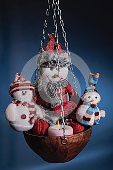 Three snowmen warming themselves by the hearth from candle