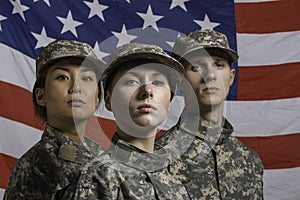 Three soldiers posed in front of American flag, horizontal