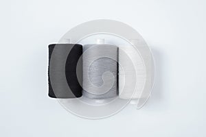 Three spools sewing thread lying in a row. White background