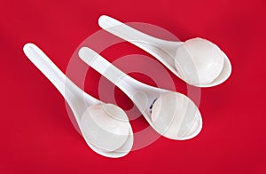 Three spoons with dumplings on the red background