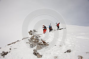 Three sportsmen with equipment hiking up the mountain