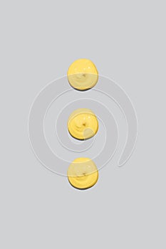 Three spots of yellow paint on a gray background. Cream, cosmetic, topping for your design