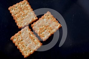Three square cookies on a dark background