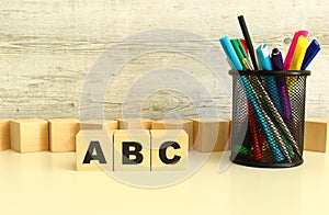 Three stacked wooden cubes with letters ABC on a white desktop on a gray background.