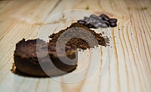 Three stages for preparation of coffee: grain, crushing and the pressed tablet. Wooden surface. Espresso. Work barista.