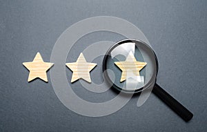Three stars and a magnifying glass on a gray background. Authentication of the third star, rating fraud. Rating and status of the photo