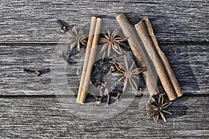 Three sticks of cinnamon, four star fruit of star anise and cloves on old boards photo