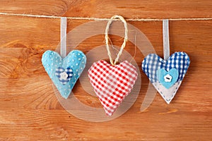 Three stitched red hearts made of cloth hanging on a clothesline