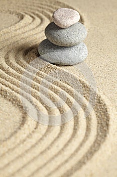 Three stones stacked on raked sand