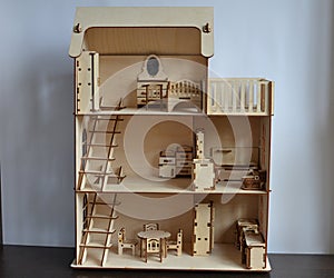 Three-storey wooden doll house with furniture and stairs.