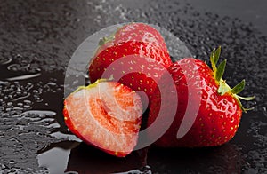 Three strawberries on black with water drops