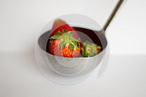 Three strawberries in ladle (dipper)