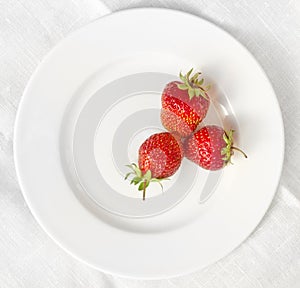 Three strawberries on a white plate