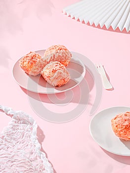 Three strawberry snowballs in a porcelain bowl and single one served in white plate on a pink table