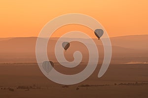 Three striped balloons fly over purple hills