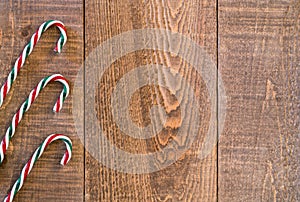 Three striped candy canes along left border of rustic wooden surface