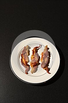 Three Strips of Cooked Bacon on White Plate