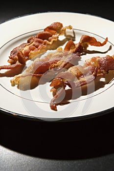 Three Strips of Cooked Bacon on White Plate