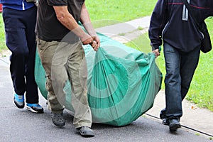 three strong men are dragging a huge green bag with an inflatable trampoline. Events for the City Day