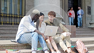 three students discussing internet news while sitting on the steps.