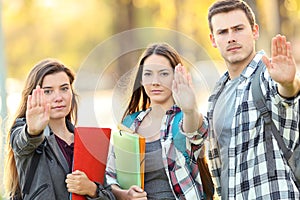 Three students gesturing stop in a park