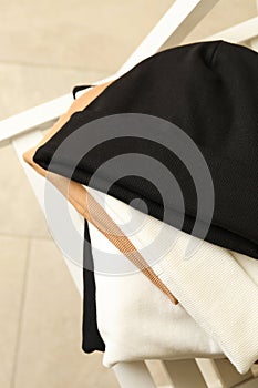 Three stylish beanies on wooden chair, close up