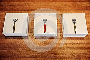 Three stylish razors with boxes on the wooden table