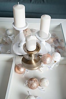 Three Stylish white large candles on the table, and New Year`s balls, photos in gentle pastel colors. Christmas mood