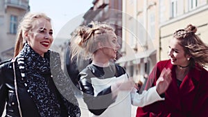 Three stylish woman gathered together and walking down the street laughing and communicating. Stylish outlook, beauty