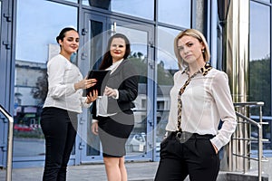 Three successful business ladies standing in front of central entrance of office