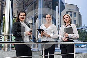 Three successful business ladies standing in front of central entrance of office