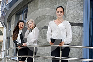 Three successful business ladies standing in front of central entrance of office