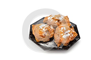 Three sugared fried fritters or oliebollen on saucer