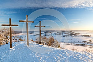 Three summit crosses on a mountain peak in a beautiful winter landscape in the Swabian Alps at sunset