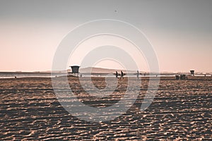 Three surfers walk along the beach in California