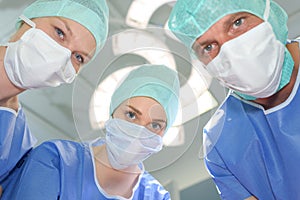 three surgeons at work operating in surgical theatre