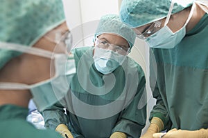 Three Surgeons At Work In Operating Theatre